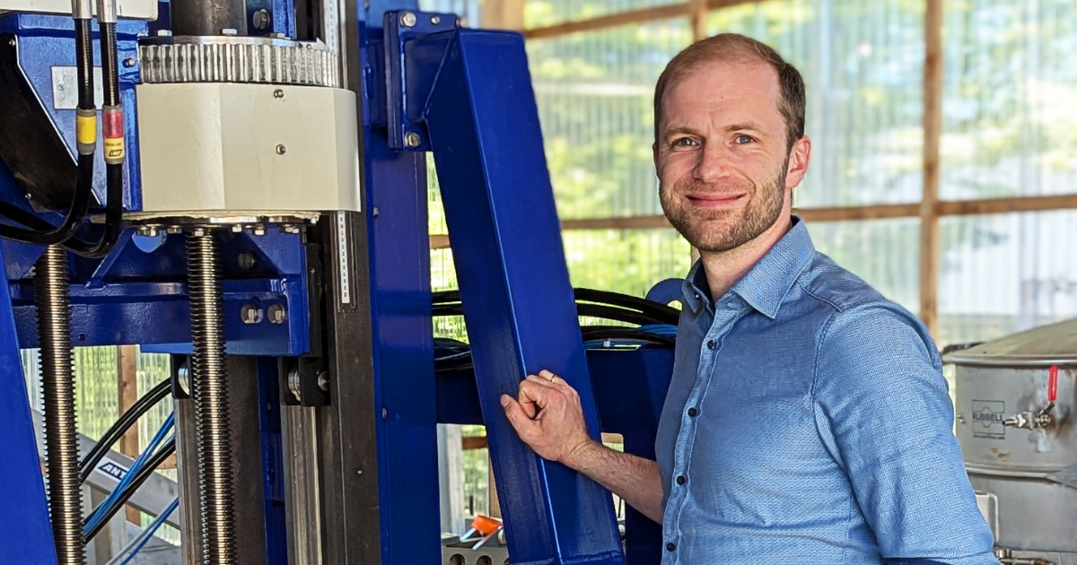 zeigt einen Head of Engineering mit blauem Hemd an einer Maschine